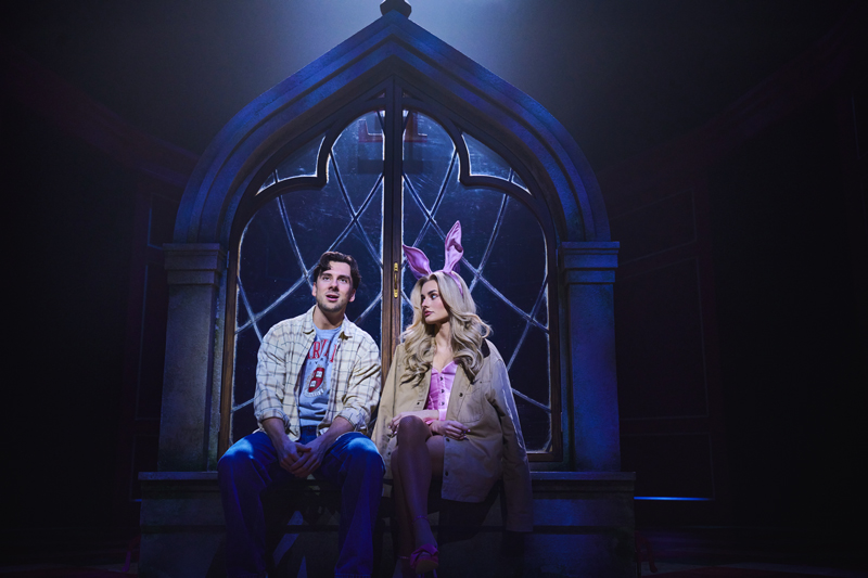 A white woman in her 20s and a white man in his 20s as Elle and Evan from Legally Blonde. Elle wears bunny ears and looks sad