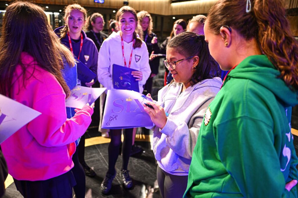 Students from Richard Lander school smile on as the cast of SIX the Musical sign their programmes