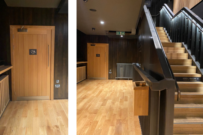 A photo of a light brown door to some of the toilets at Hall for Cornwall on the lefthand side of the stage, with stairs to the right of it also. 