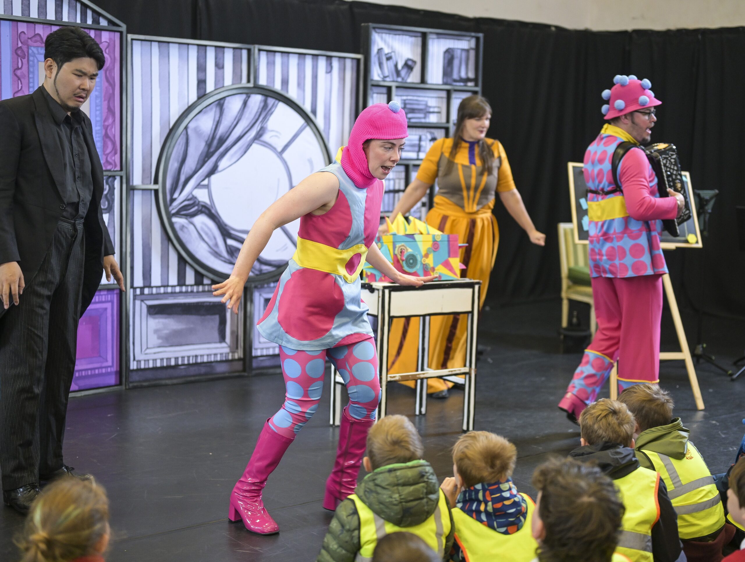 Performers from English Touring Opera, dressed in brightly coloured costumes, perform for students